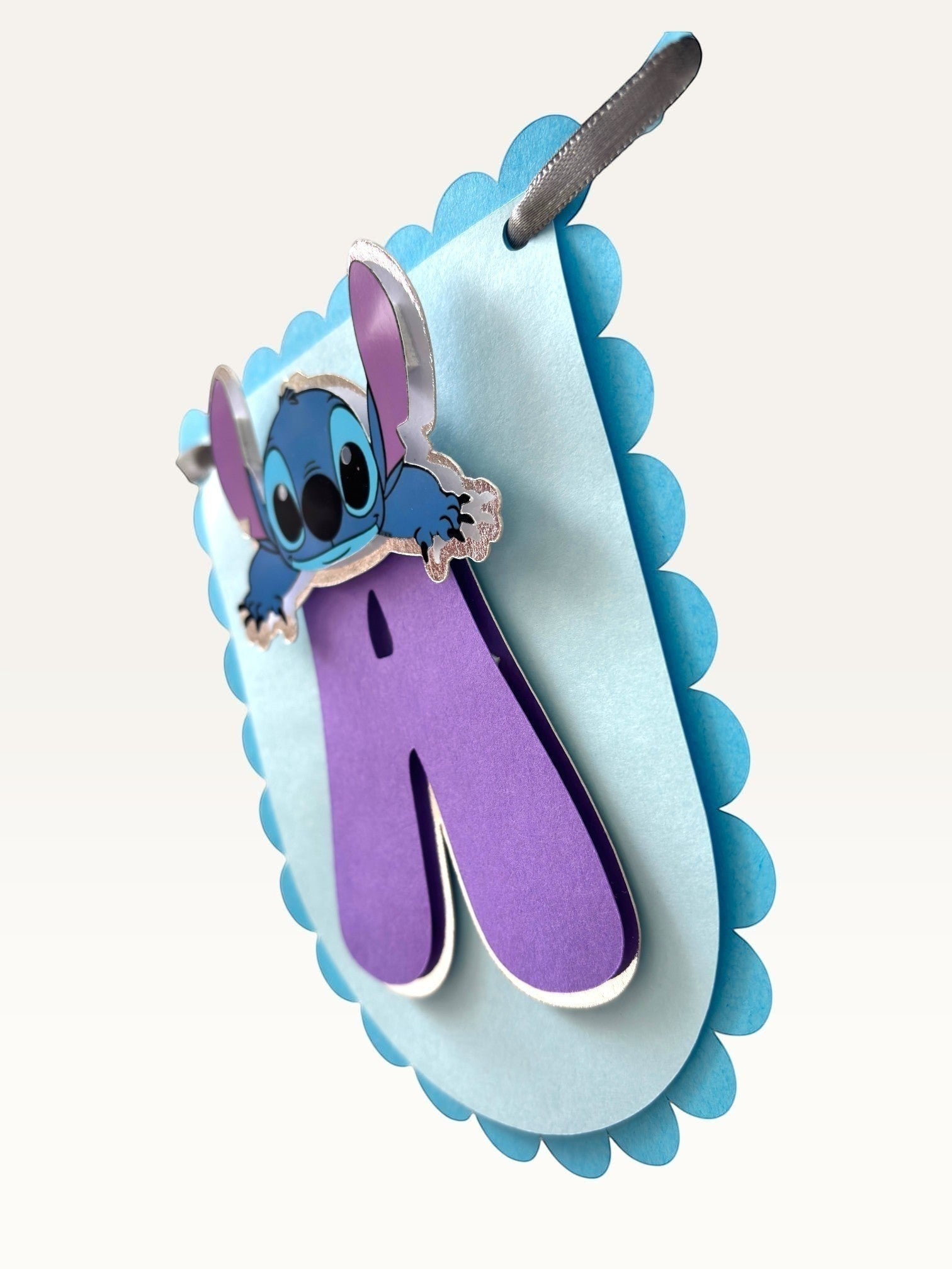 Paper Party Studio blue scalloped cardstock birthday banner with purple letter and cute alien character detail.