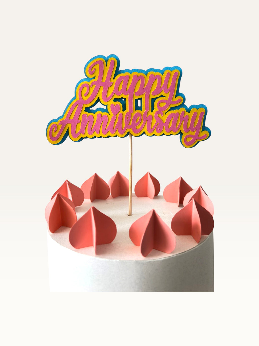 Paper Party Studio layered script Happy Anniversary cake topper in pink and blue on a wooden pick.