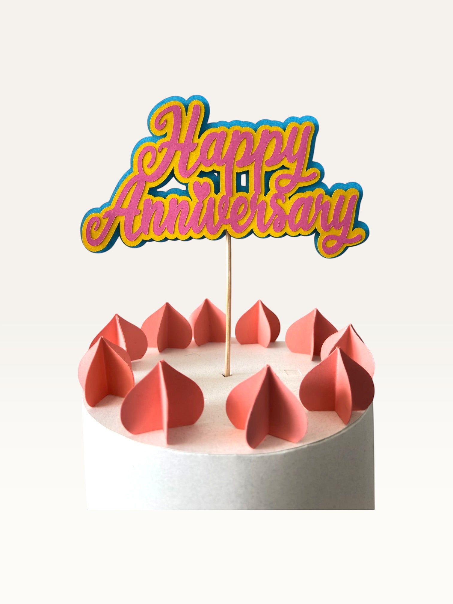 Paper Party Studio layered script Happy Anniversary cake topper in pink and blue on a wooden pick.