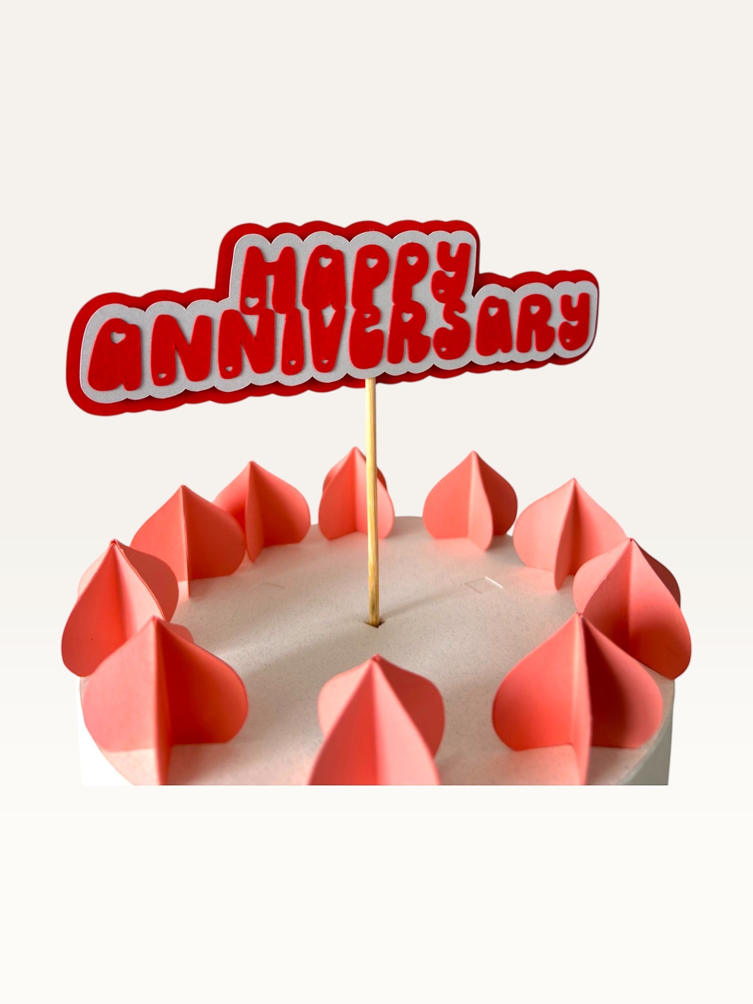 Paper Party Studio handmade red and white Happy Anniversary cake topper with heart cut-outs on a wooden pick