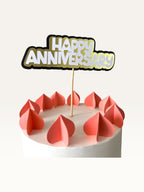 Paper Party Studio Happy Anniversary cake topper with white, gold, and black layered cardstock and heart cut-outs.