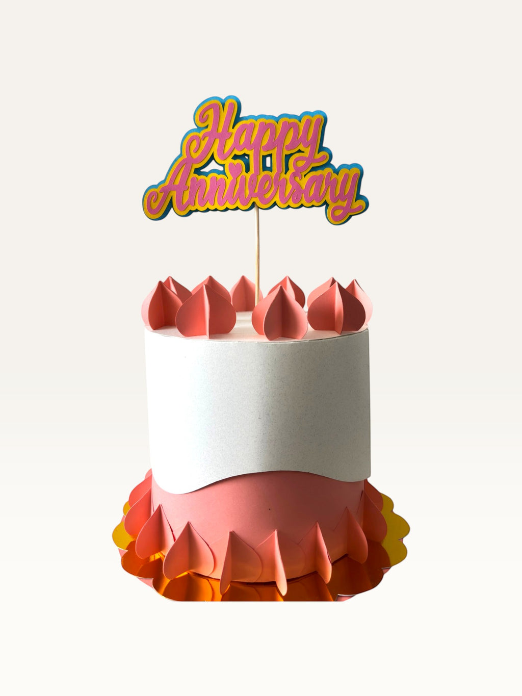 Paper Party Studio layered script Happy Anniversary cake topper in pink and yellow on a decorative paper cake