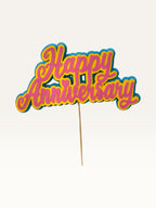 Paper Party Studio layered cardstock Happy Anniversary cake topper in pink, yellow, and blue script with heart detail