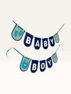 Paper Party Studio navy and sage Baby Boy cardstock banner with baby-themed cut-outs for baby shower decorations.