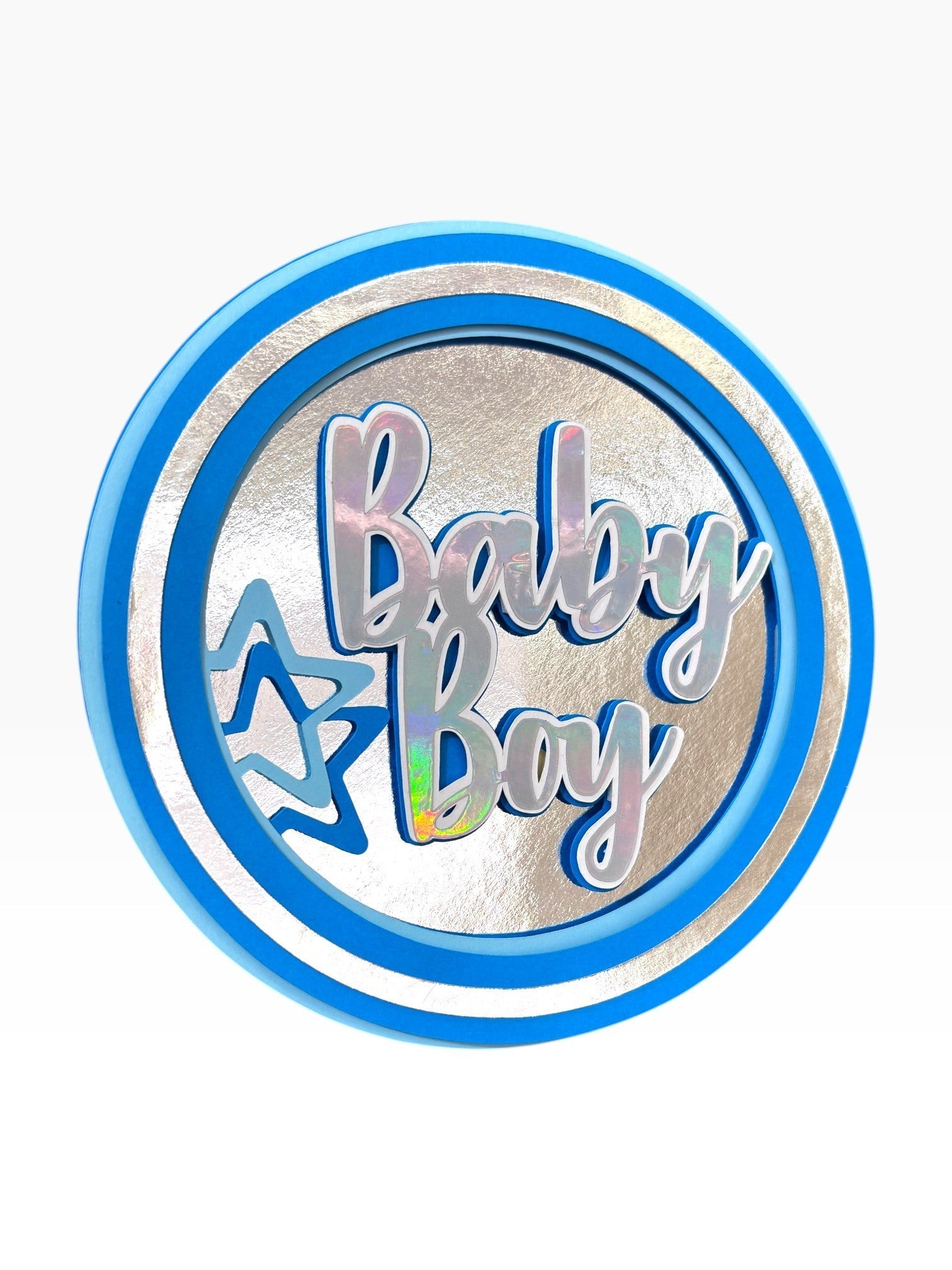 Paper Party Studio Baby Boy holographic foil cake topper with blue and silver layered circular design and star accents.