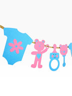 Paper Party Studio baby shower garland with blue onesie, pink teddy bear, and blue baby bottle cutouts on gold cord.