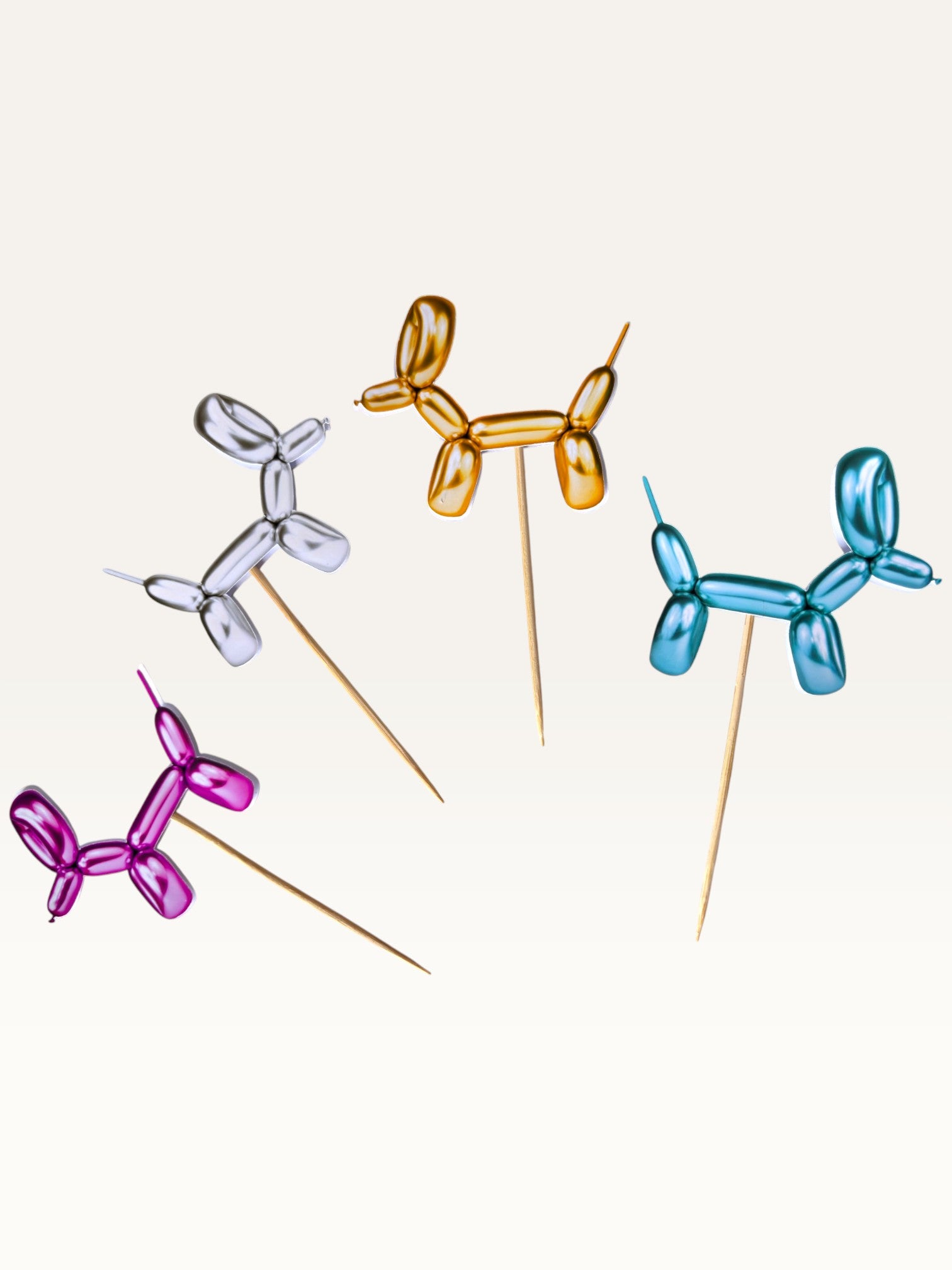 Paper Party Studio balloon dog cake toppers in metallic silver, gold, blue, and pink on bamboo sticks.
