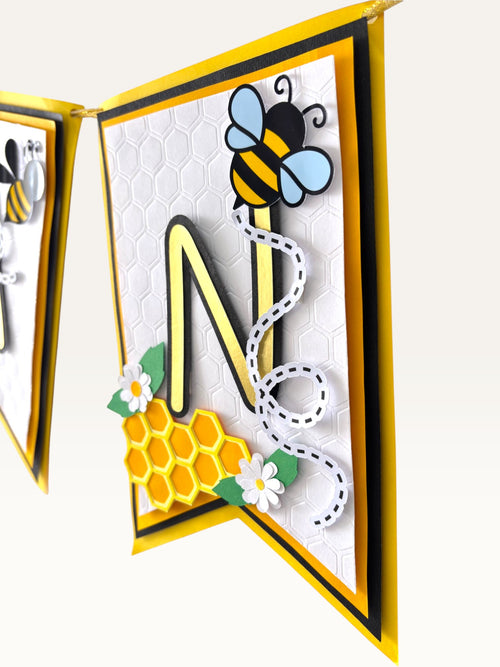 Paper Party Studio personalised bee theme birthday banner with gold foil letter N on layered honeycomb textured flags