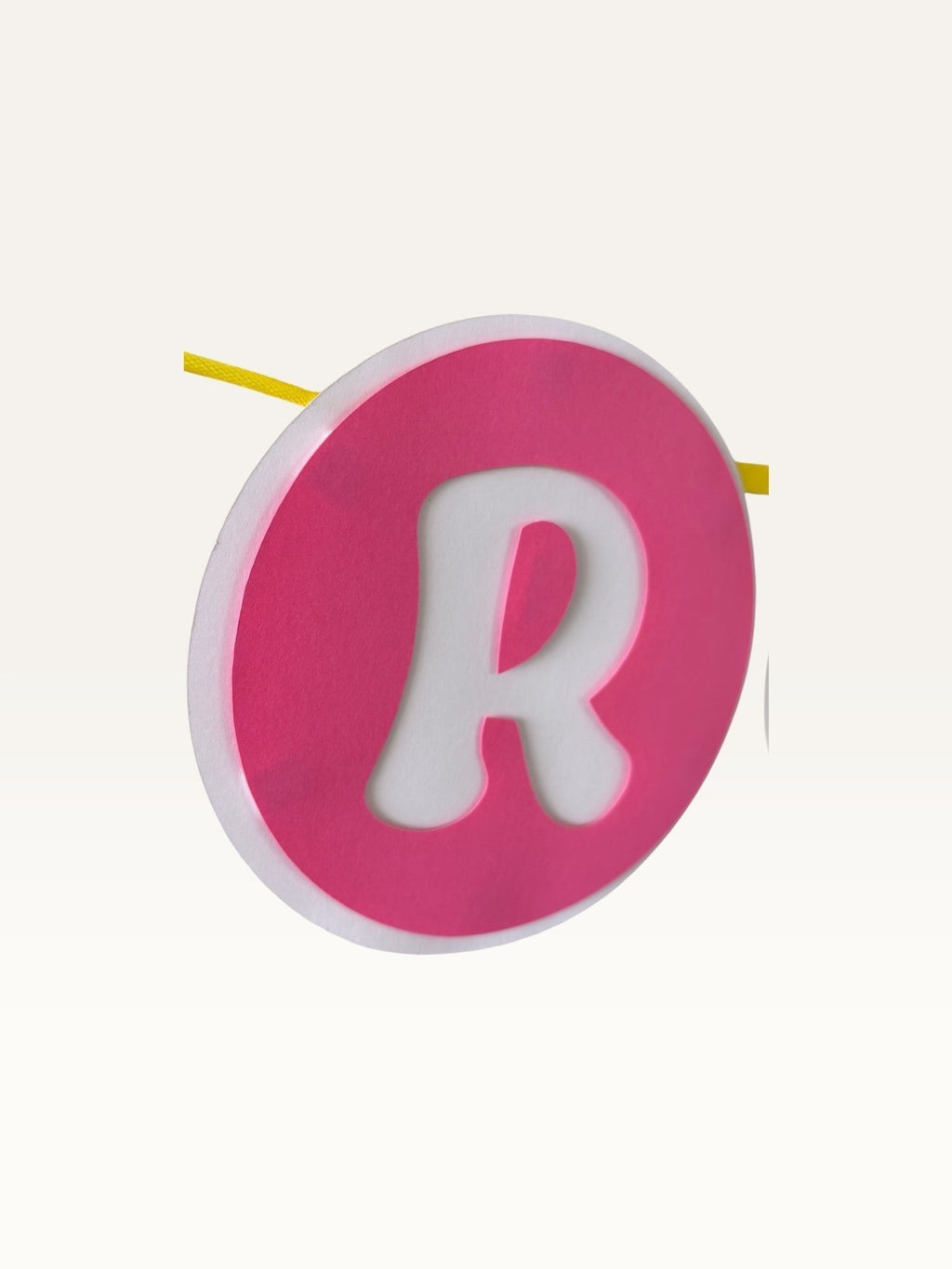 Paper Party Studio pink cardstock circle with white letter R from a rainbow birthday bunting banner