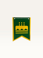 Paper Party Studio swallowtail birthday bunting flag in green cardstock with a yellow cake icon cutout.