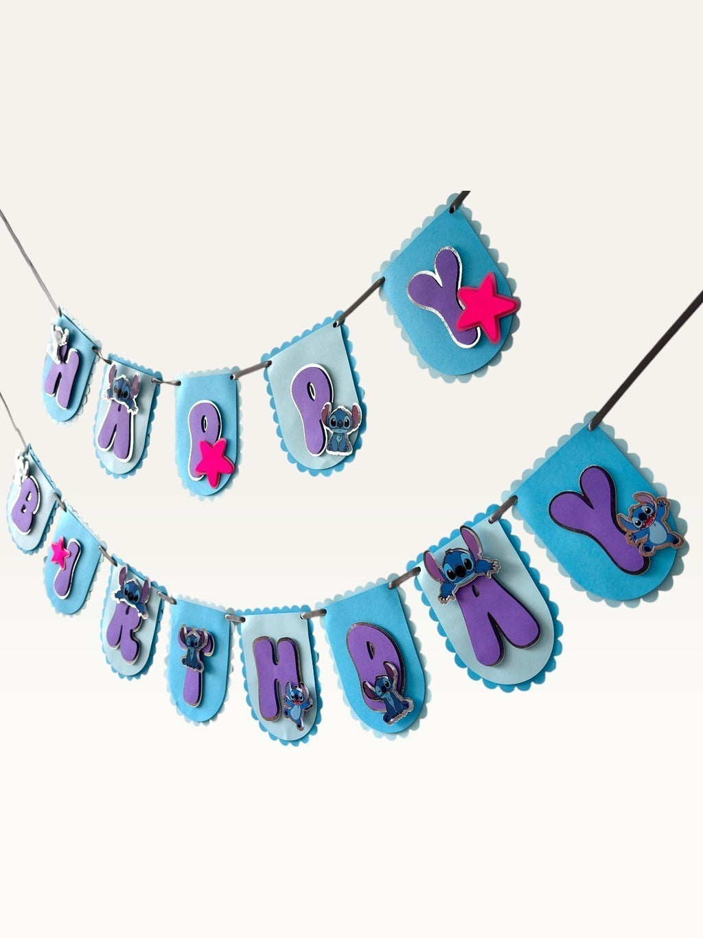 Paper Party Studio blue scalloped Happy Birthday bunting with purple letters, alien characters, and pink star accents.