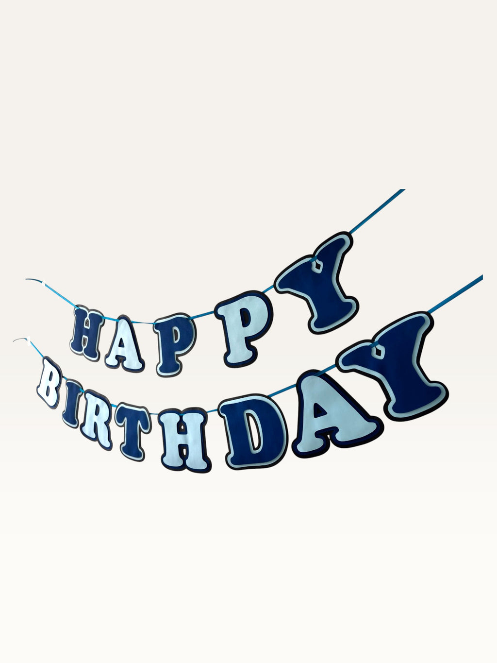 Paper Party Studio layered blue Happy Birthday banner with dimensional cut-out letters on a hanging cord.