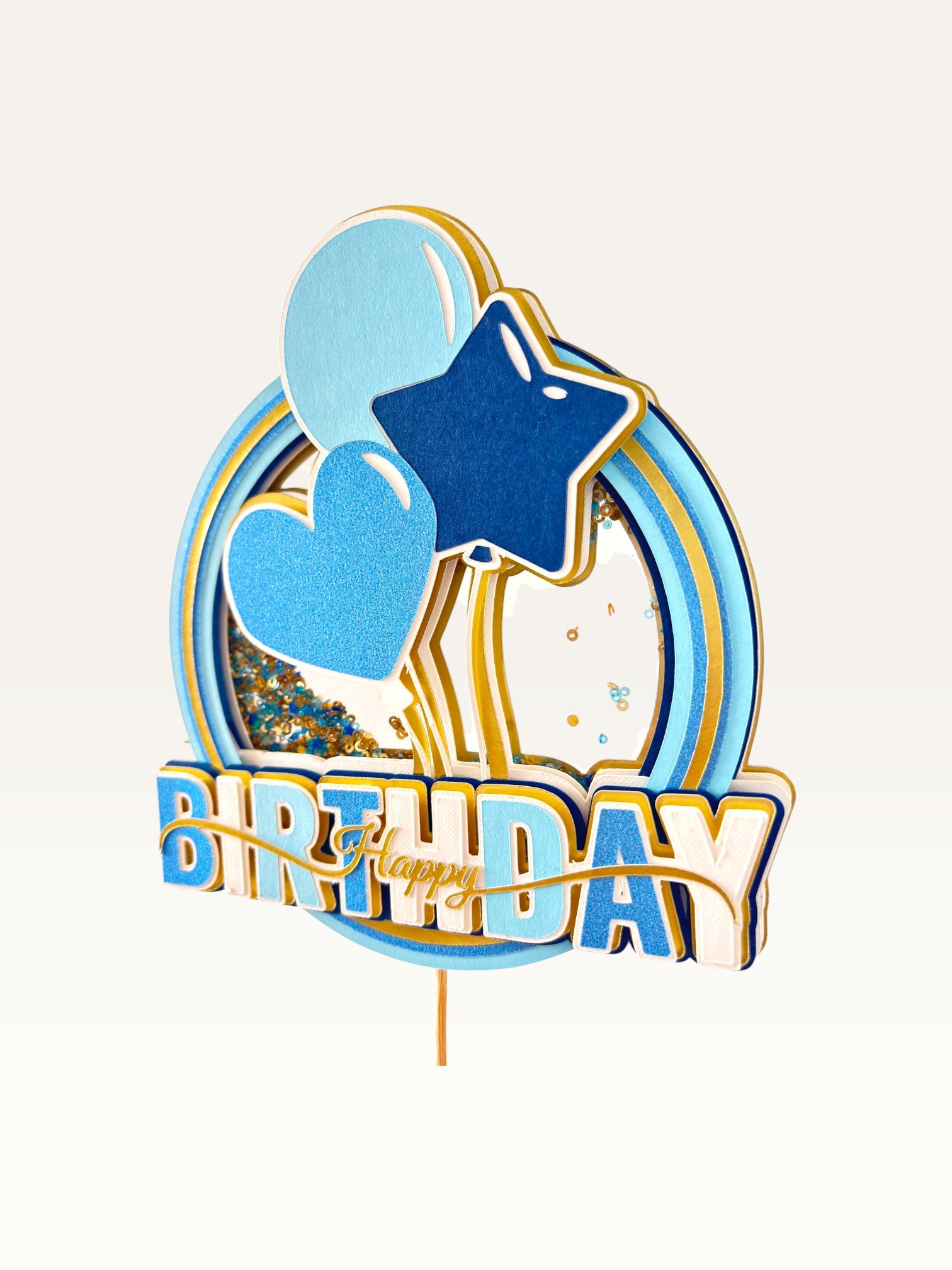 Paper Party Studio blue and gold glitter shaker cake topper with heart, star, and balloon accents.