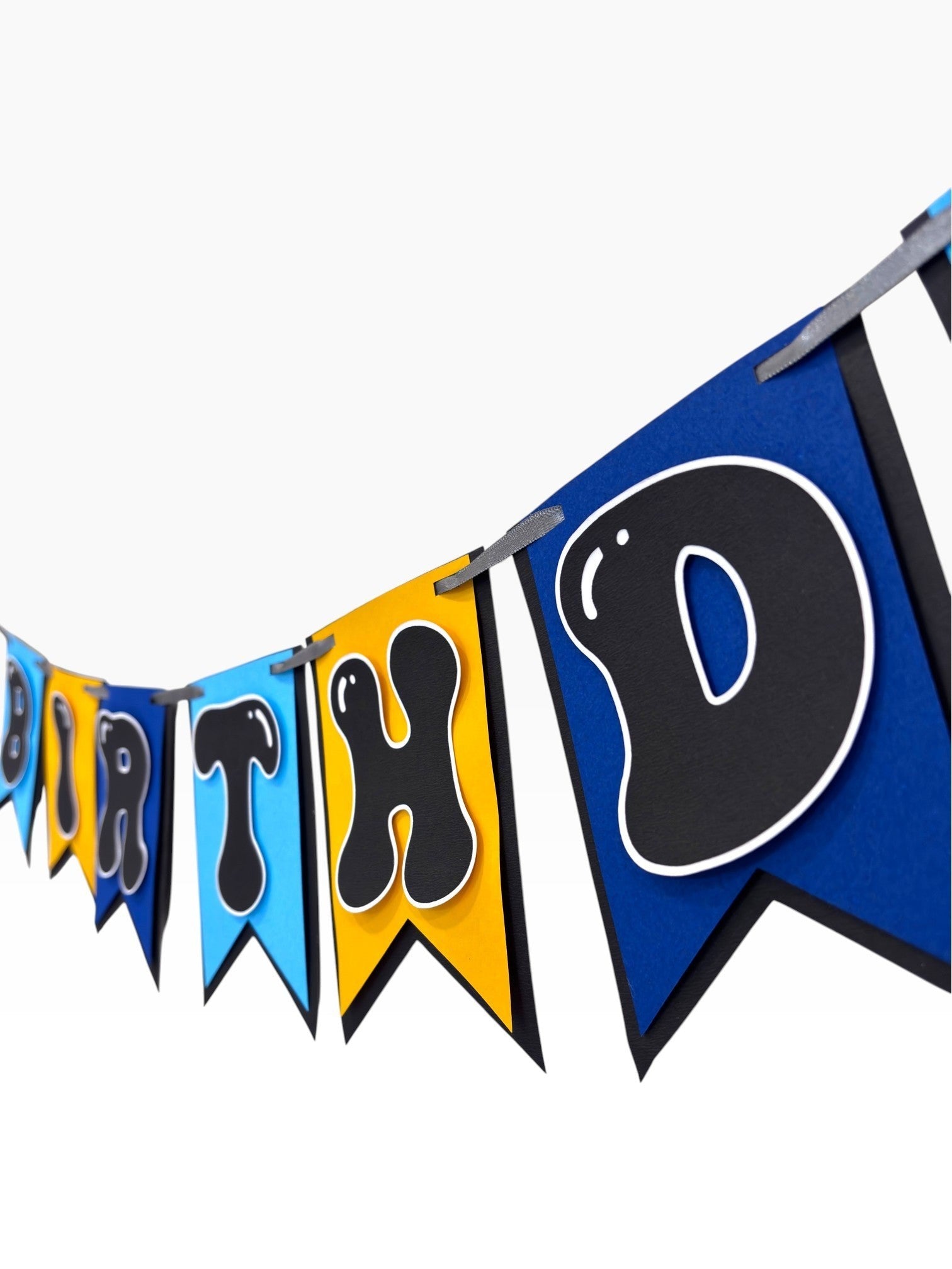 Paper Party Studio blue, sky blue, and gold paper birthday banner with bubble letters on swallowtail flags.