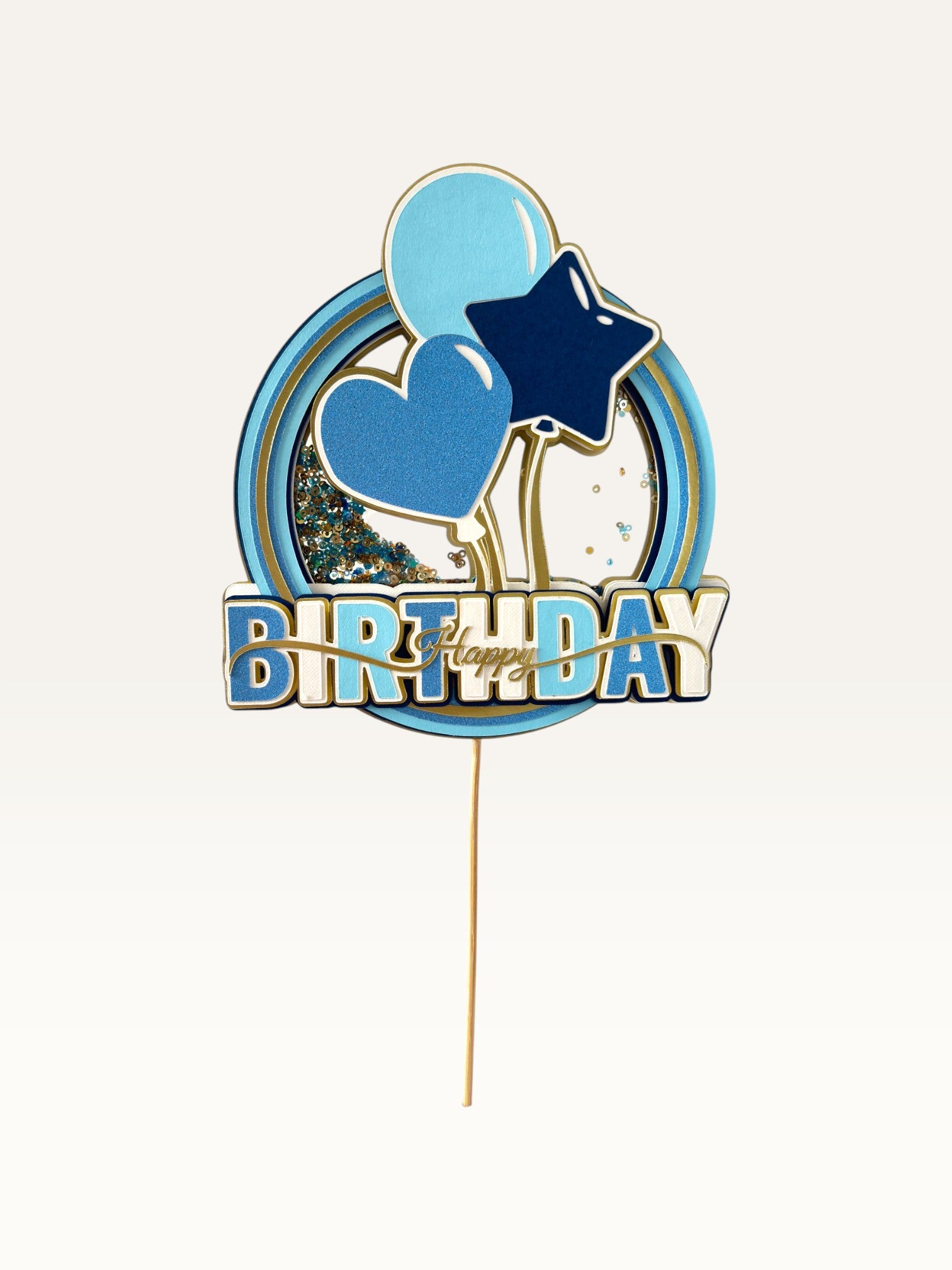 Paper Party Studio blue and gold Happy Birthday shaker cake topper with glitter, sequins, and balloon motifs.