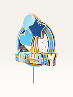 Paper Party Studio blue and gold Happy Birthday shaker cake topper with glitter, sequins, and balloon decorations.