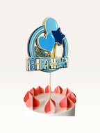 Paper Party Studio blue and gold Happy Birthday shaker cake topper with glitter, sequins, and balloon decorations.