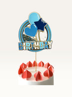 Paper Party Studio blue Happy Birthday cake topper with a glitter and sequin shaker center, balloons, and gold accents.