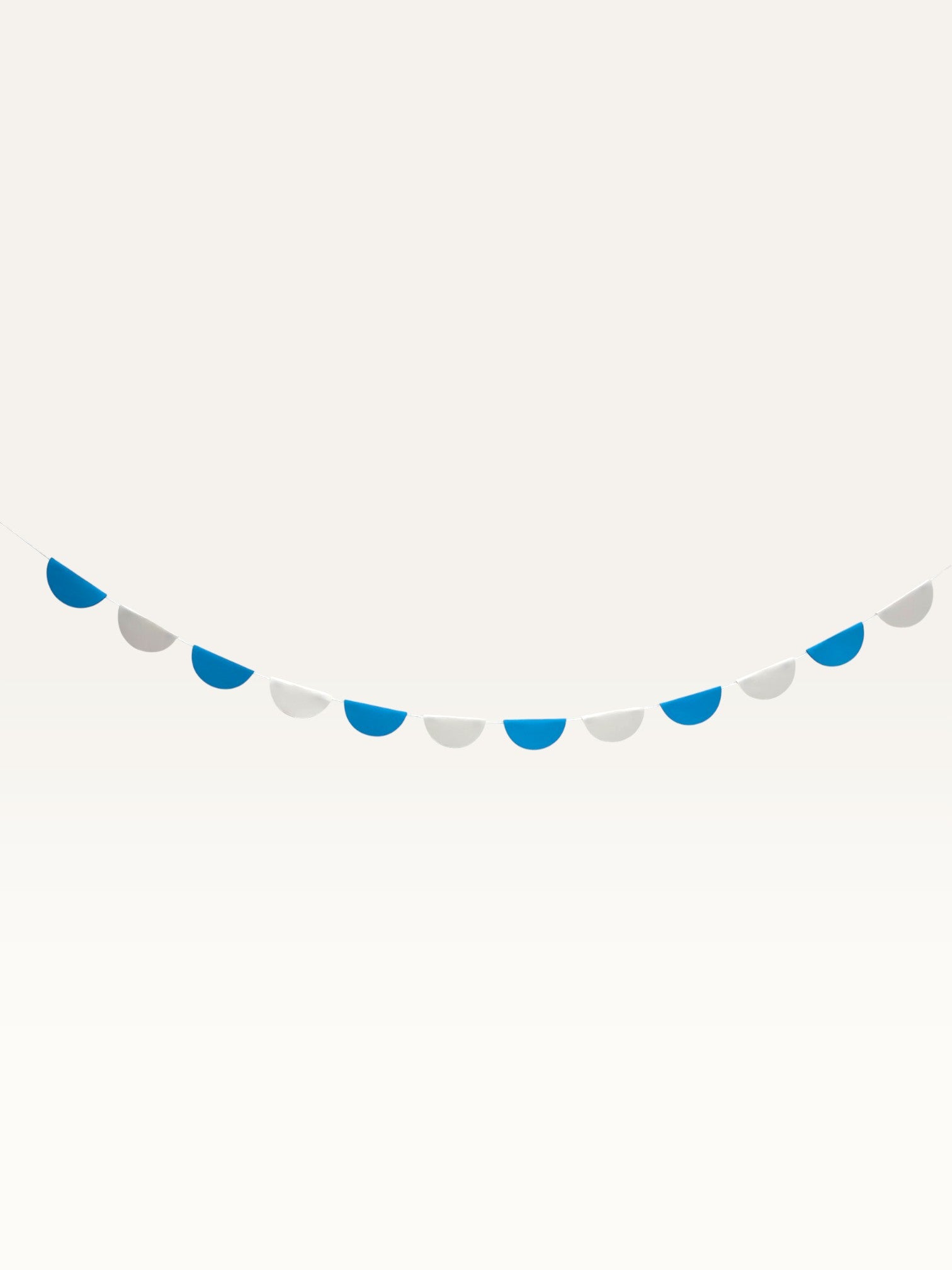 Paper Party Studio blue and white paper scallop garland hanging as a decorative wall banner for parties and nurseries.