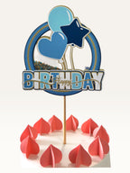 Paper Party Studio blue and yellow birthday cake topper with heart and star balloons on a white cake