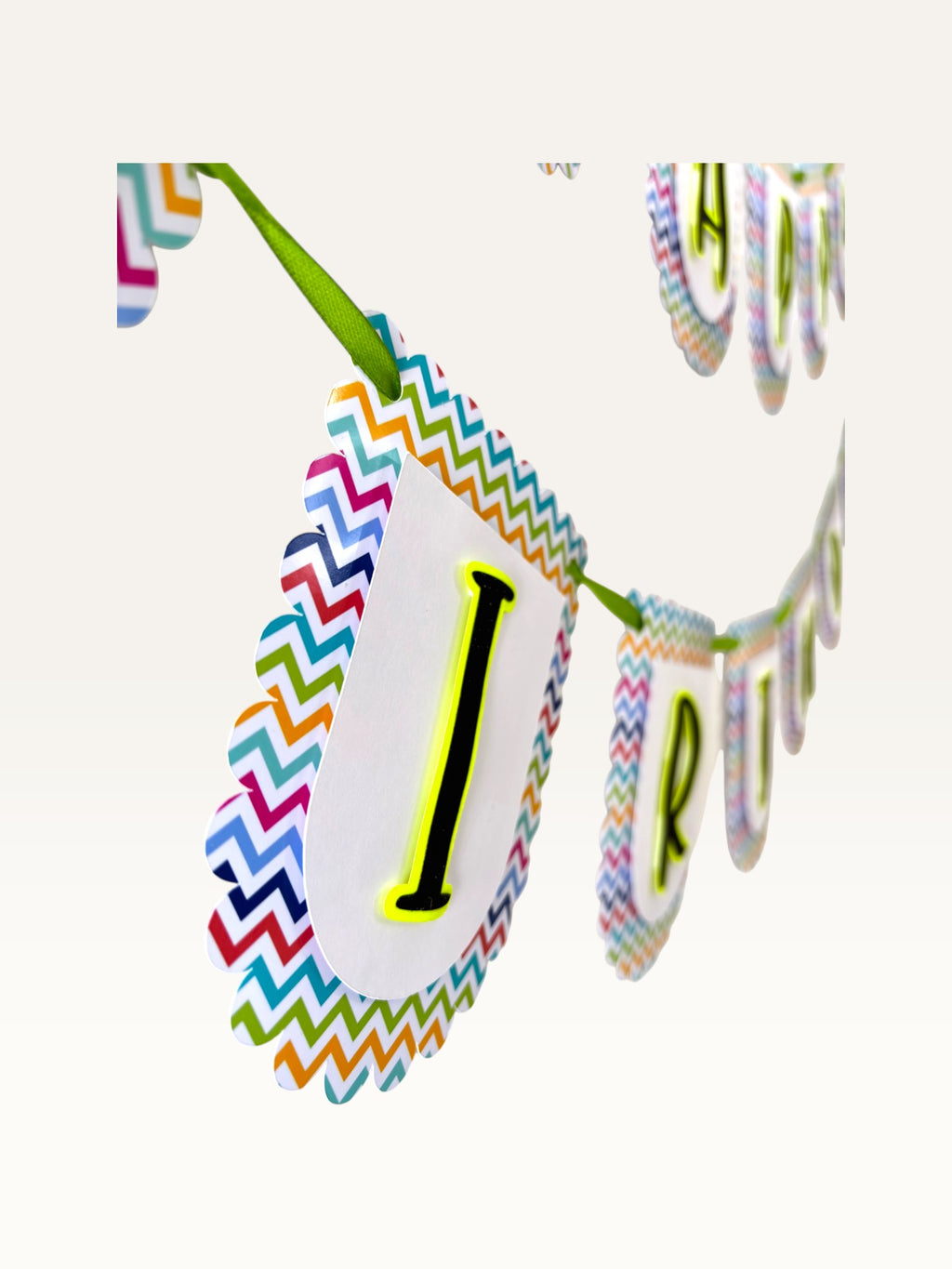 Paper Party Studio Happy Birthday banner with white scalloped tags, multicolour chevron borders, and black letters.