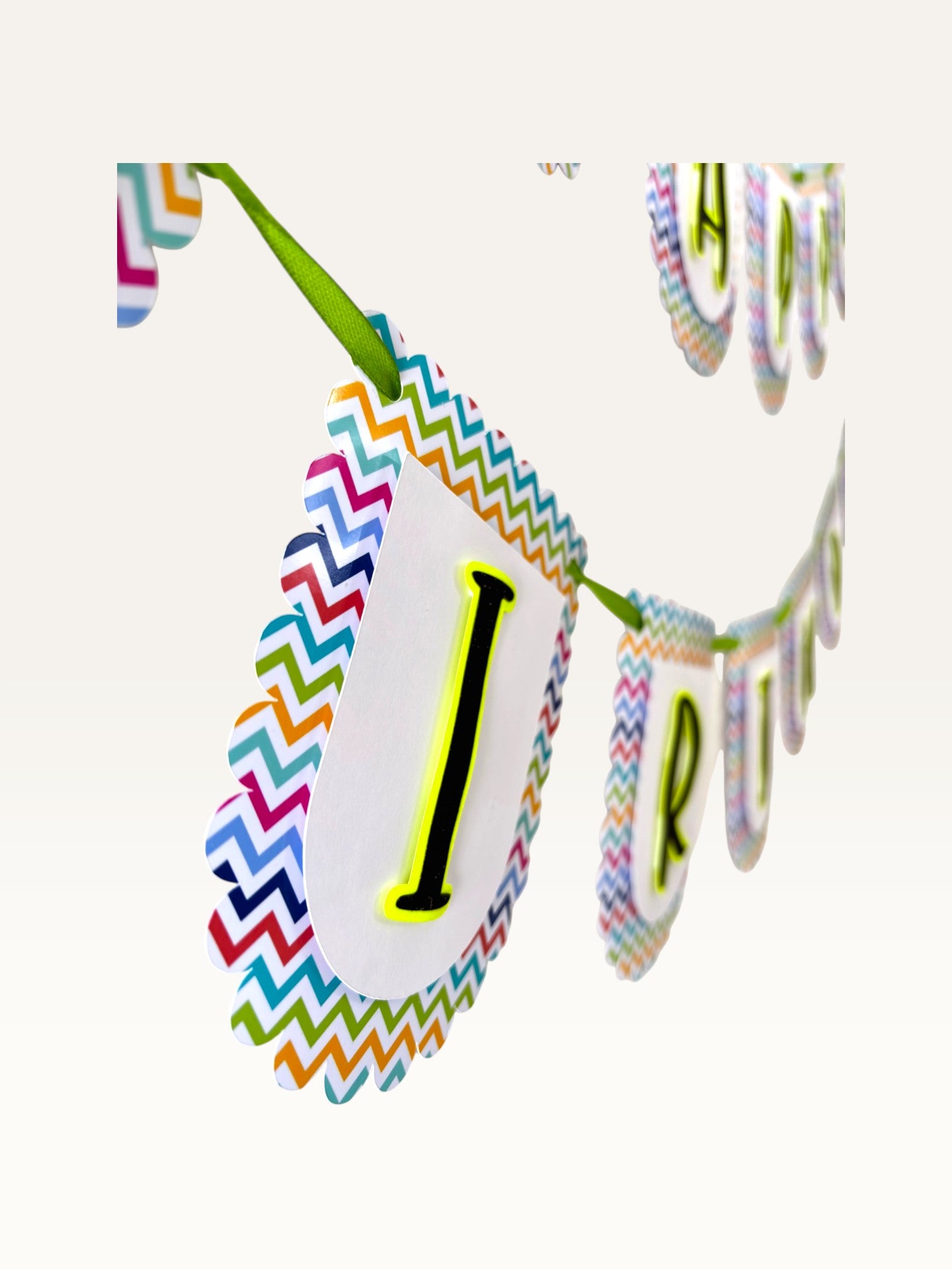 Paper Party Studio Happy Birthday banner with white scalloped tags, multicolour chevron borders, and black letters.