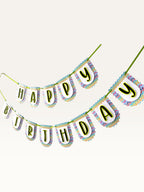 Paper Party Studio Happy Birthday banner with multicolour chevron scalloped paper flags and bold black letters.