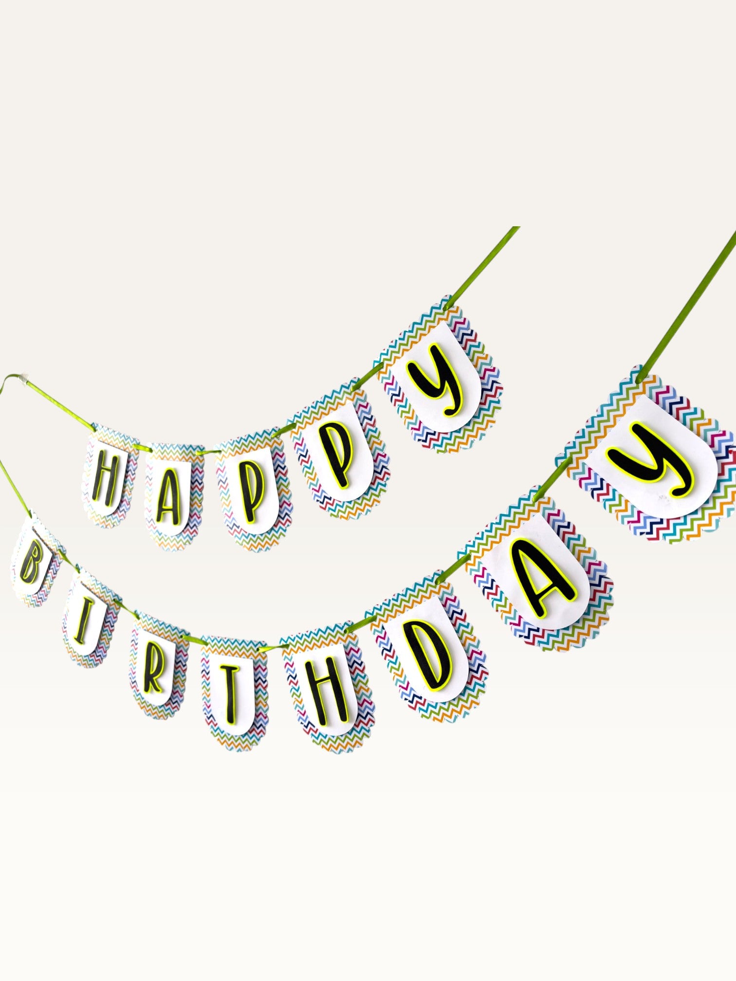 Paper Party Studio Happy Birthday banner with multicolour chevron scalloped paper flags and bold black letters.