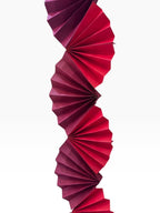 Paper Party Studio Colorwave Garland in red and pink cardstock with sculptural folded paper fan design.