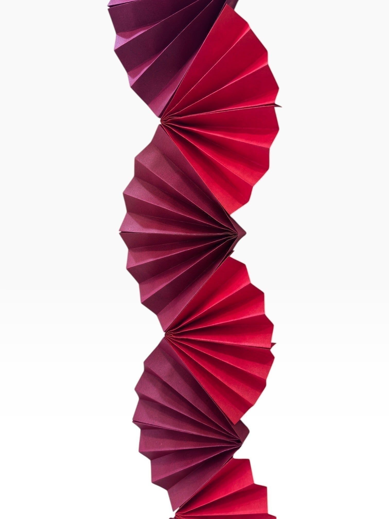 Paper Party Studio Colorwave Garland in red and pink cardstock with sculptural folded paper fan design.
