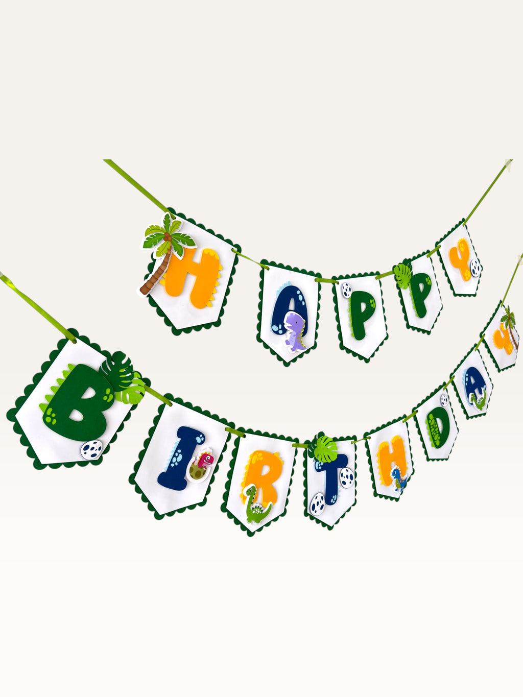 Paper Party Studio dinosaur Happy Birthday banner with scalloped white flags, jungle leaves, and colorful dino motifs.