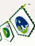 Paper Party Studio dinosaur birthday banner with scalloped white flags, green borders, and layered cardstock letters