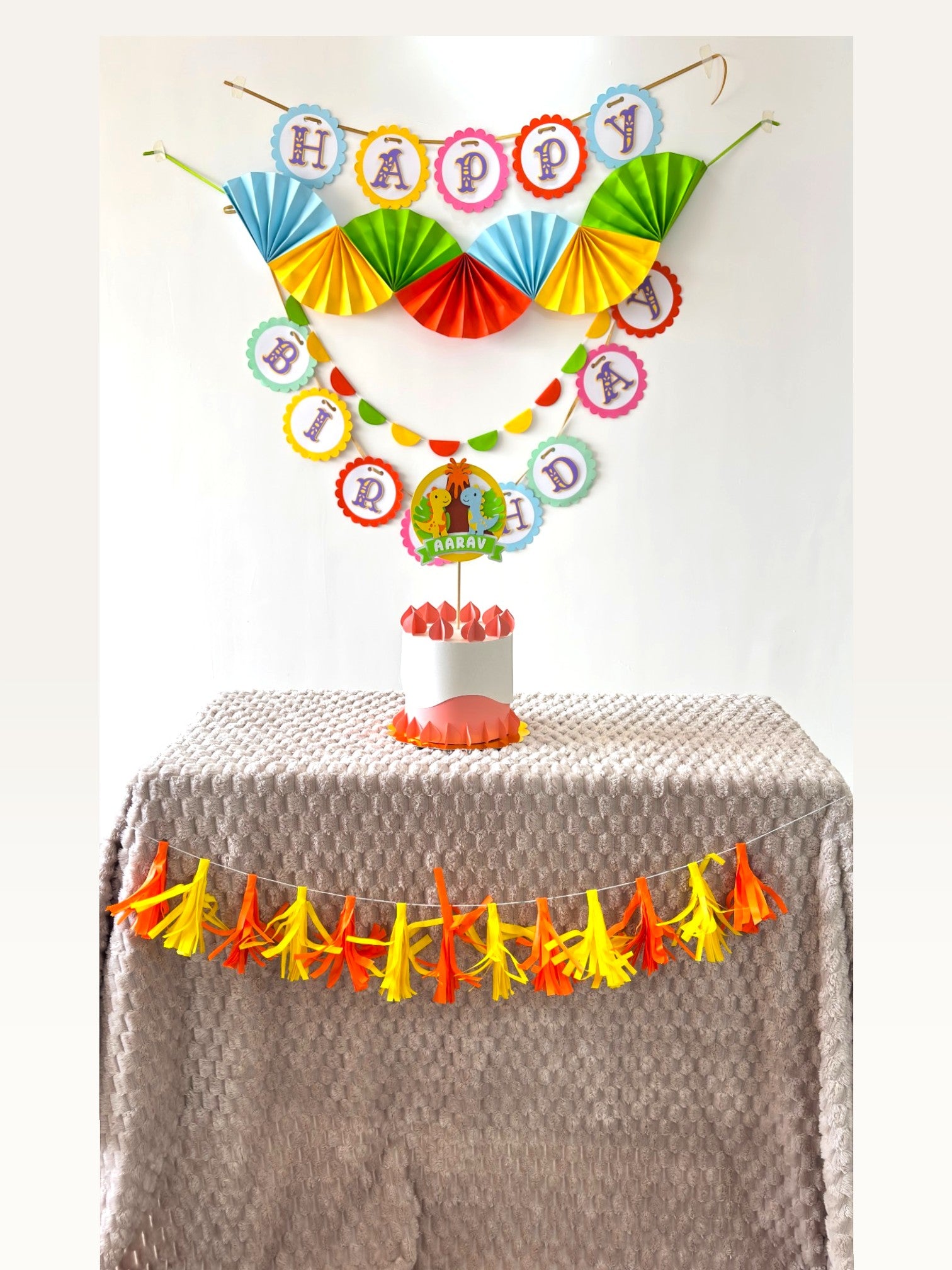 Paper Party Studio dinosaur birthday party decoration set with personalised cake topper, banners, and tassel garland.