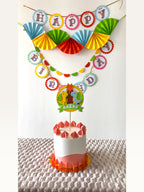 Paper Party Studio dinosaur birthday party decoration set with personalised cake topper, banner, and paper fans.