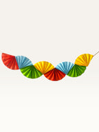 Paper Party Studio multicoloured paper fan garland for dinosaur themed birthday parties featuring red, yellow, blue, and green