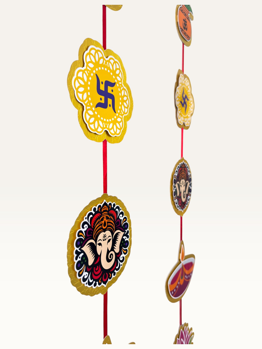 Paper Party Studio festive door hanging with layered cardstock auspicious motifs like Ganesha and Swastik on red cord.