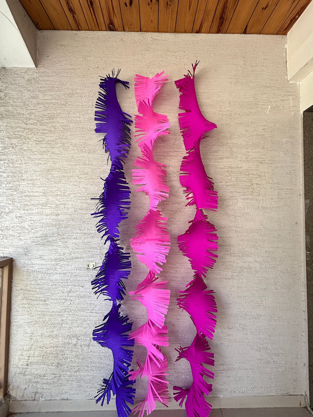 Paper Party Studio purple, pink, and hot pink crepe paper fringe streamers hanging vertically.