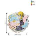 Paper Party Studio gender reveal cake topper with glitter shaker, pink and blue baby feet, and gold foil accents.