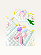 Paper Party Studio Gingham Garden birthday banner with blue check flags, pink letters, and balloon illustrations.