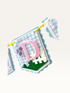 Paper Party Studio blue gingham birthday banner flag with pink letter D, white picket fence, and purple daisies