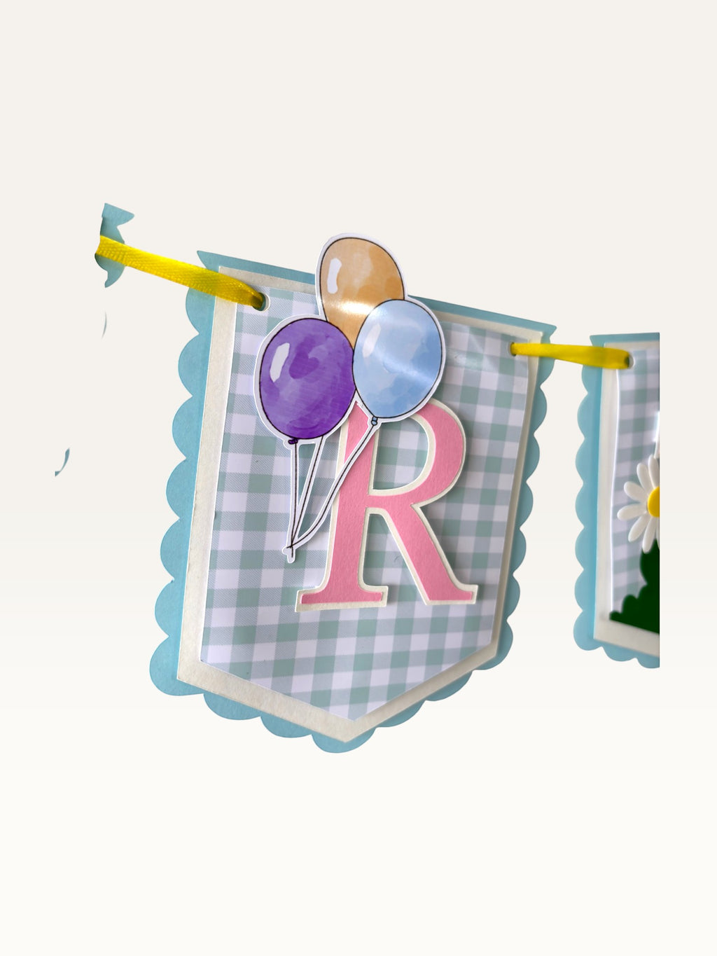 Paper Party Studio birthday banner featuring blue gingham paper flags with pink letters and balloon illustrations.