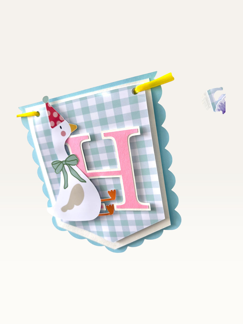 Paper Party Studio Gingham Garden birthday banner flag featuring a pink letter H, a goose in a party hat, and blue trim.