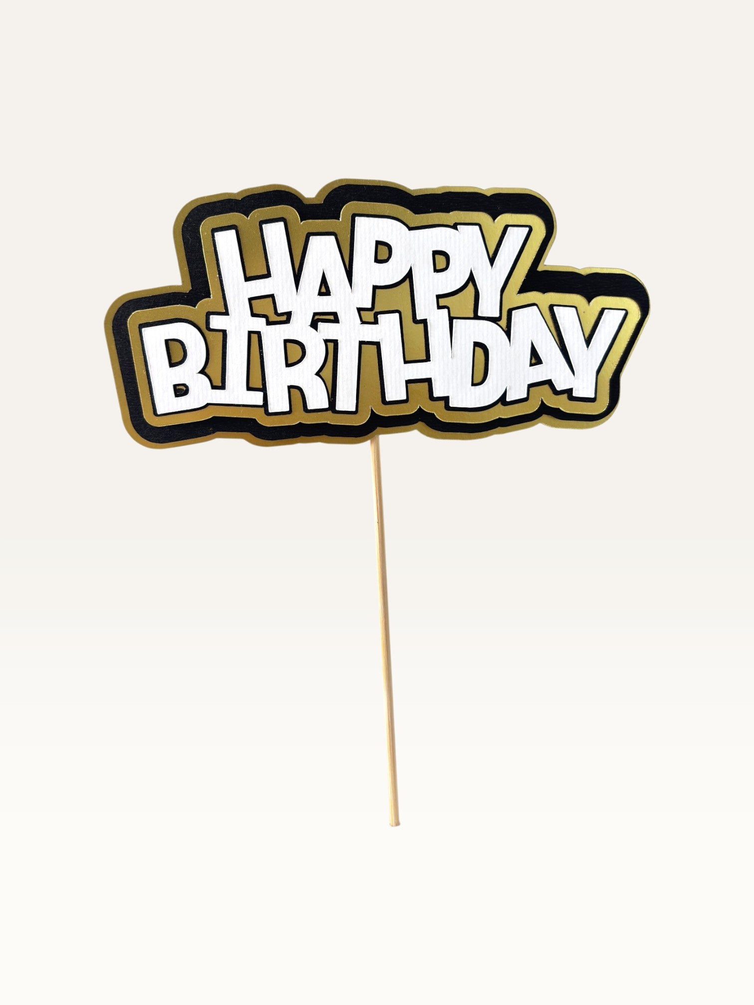 Paper Party Studio layered Happy Birthday cake topper with white lettering, black outline, and gold scalloped backing.