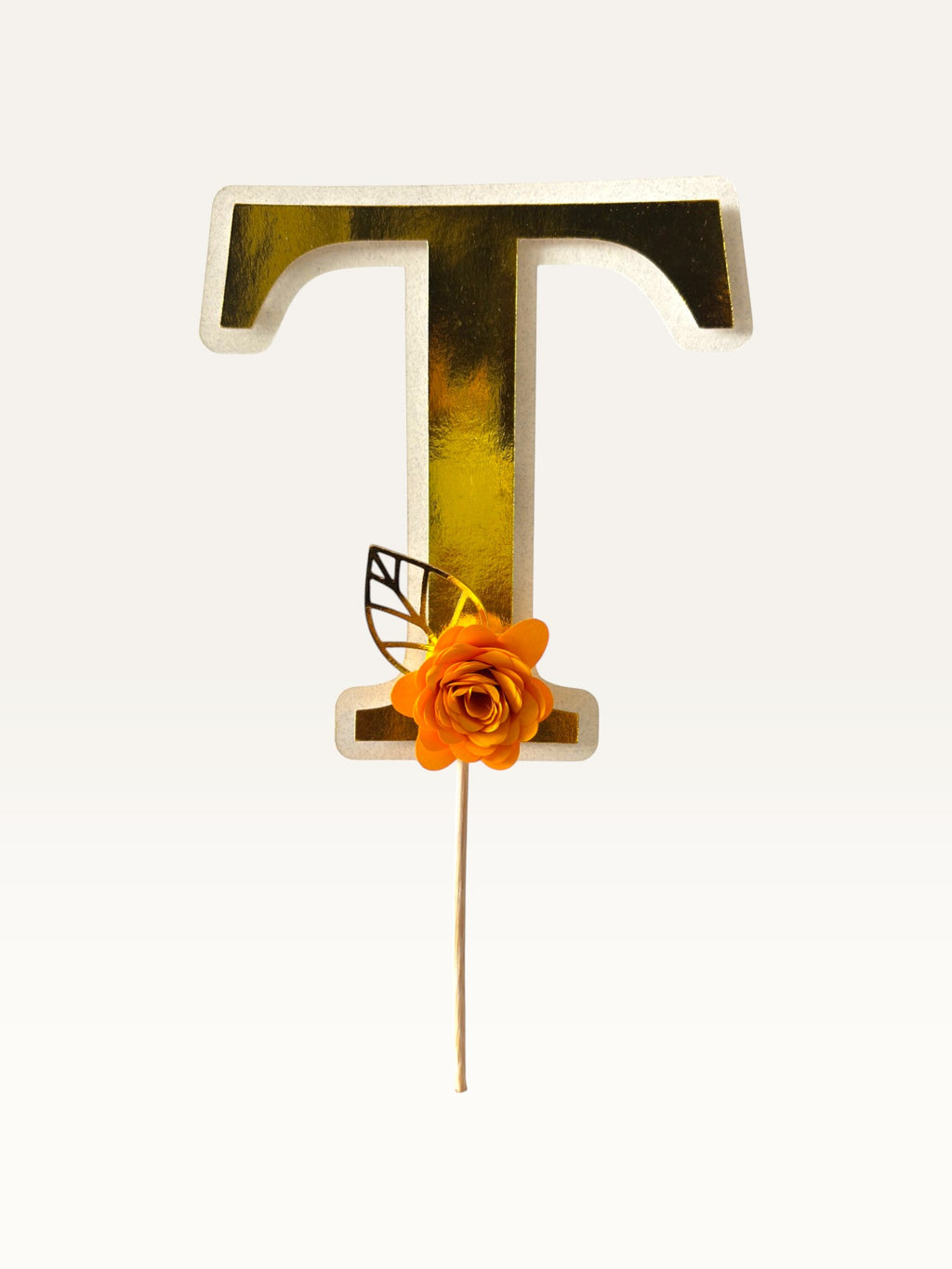 Paper Party Studio personalised gold foil letter T cake topper with an orange paper flower and gold leaf on a pick