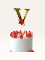 Paper Party Studio personalised gold foil letter V cake topper with a red paper flower on a wooden pick