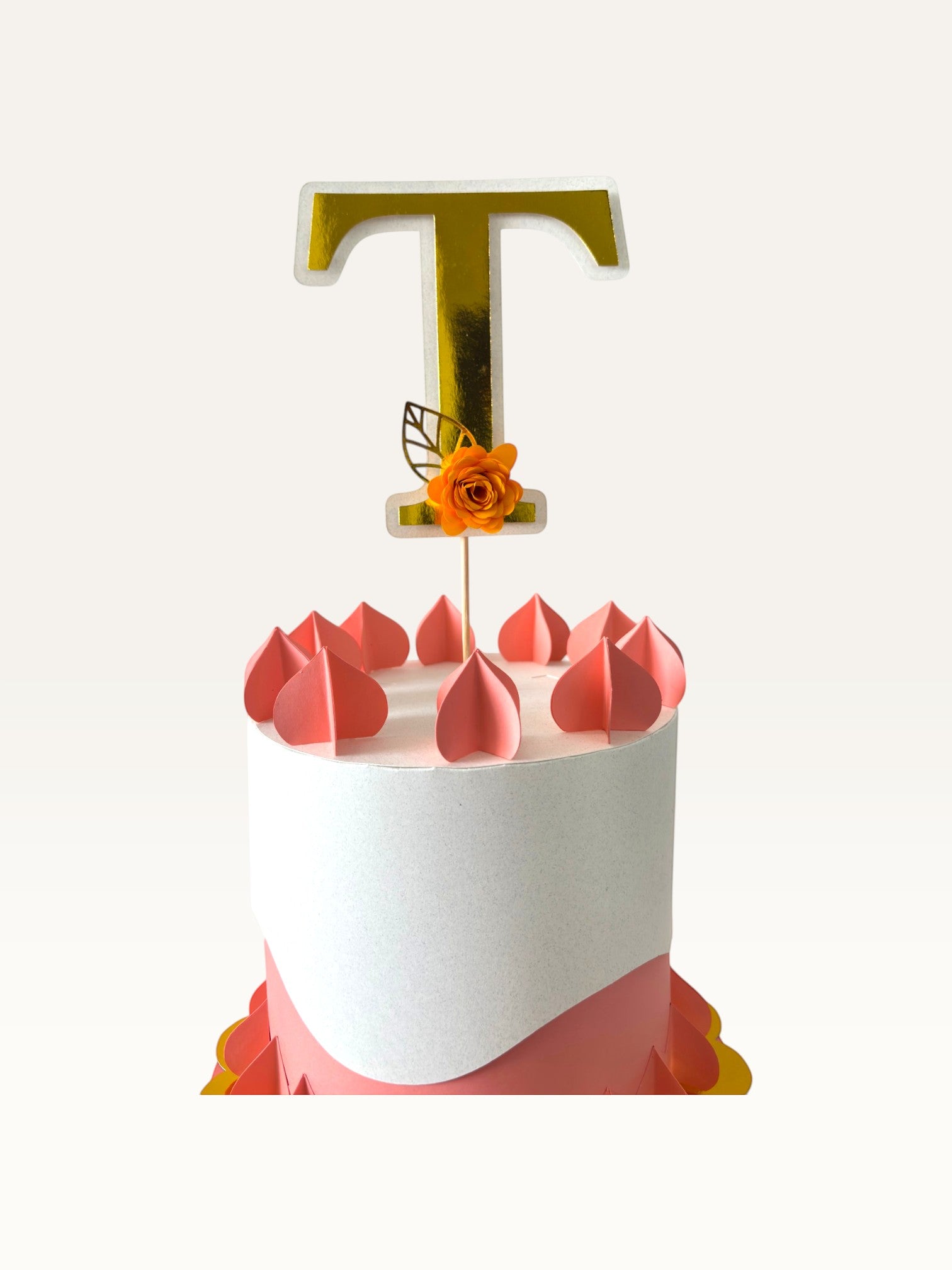 Paper Party Studio personalised gold foil letter T cake topper with an orange paper flower on a white cake