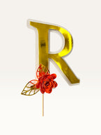 Paper Party Studio personalised gold foil letter R cake topper with a red paper flower and gold foil leaf on a pick