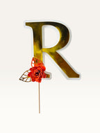 Paper Party Studio personalised gold foil letter R cake topper with a red paper flower and gold leaf on a wooden pick