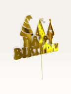 Paper Party Studio golden Happy Birthday cake topper with three party hat cut-outs on a wooden pick.