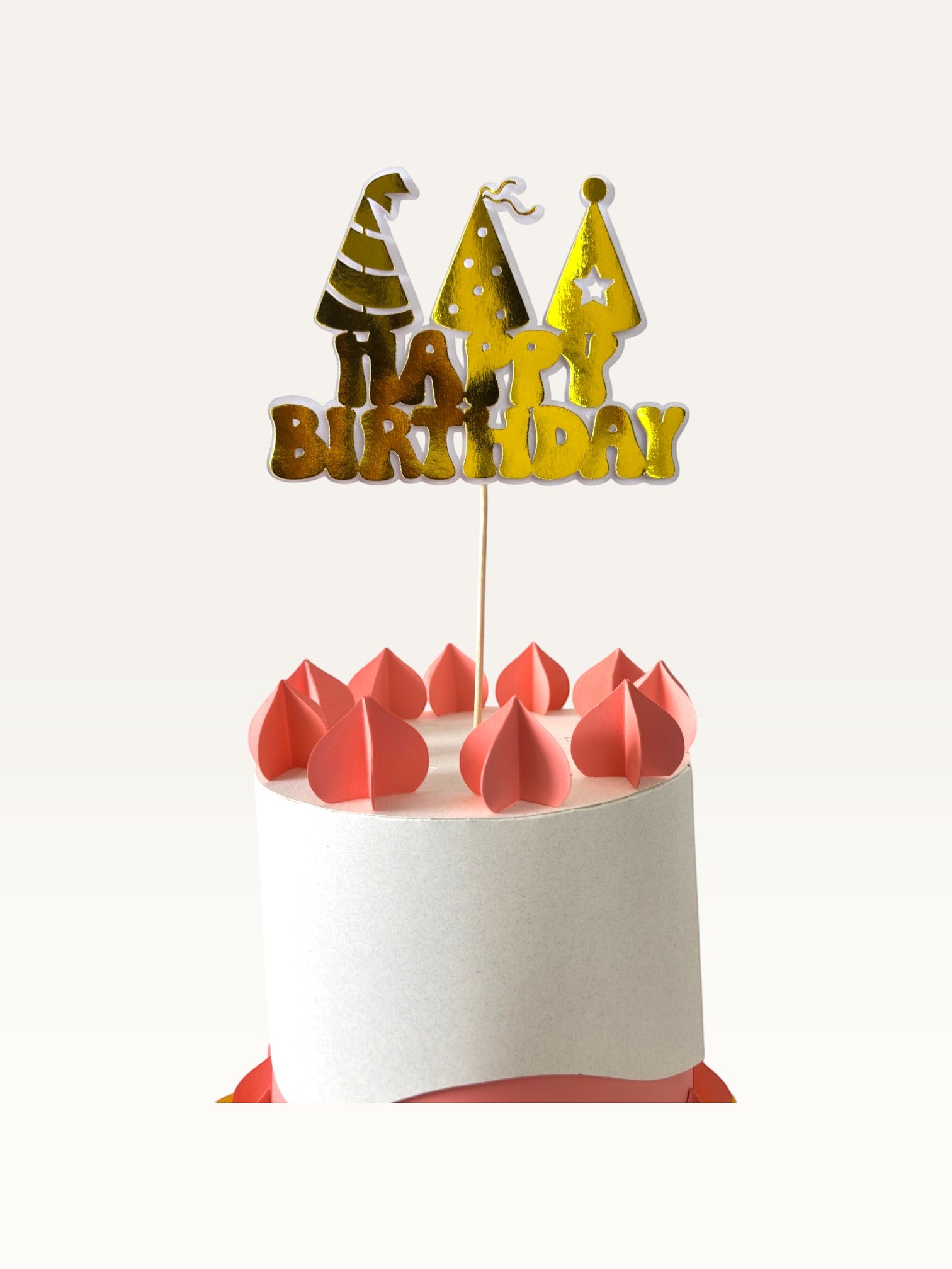 Paper Party Studio golden Happy Birthday cake topper with party hat cut-outs on a white cake